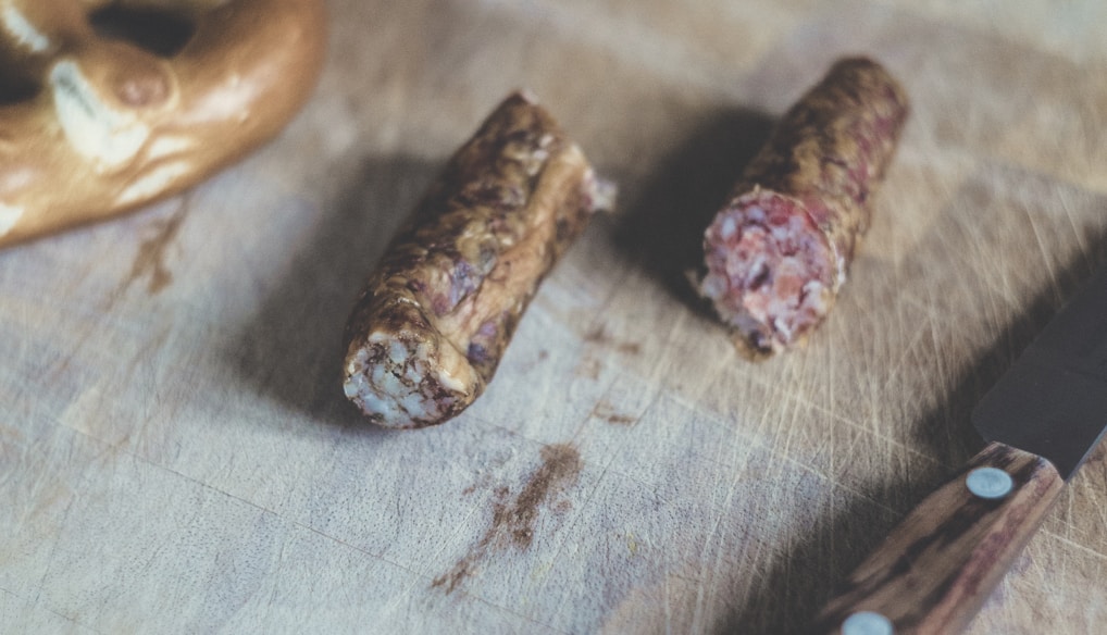 sliced sausage beside brown handle knife