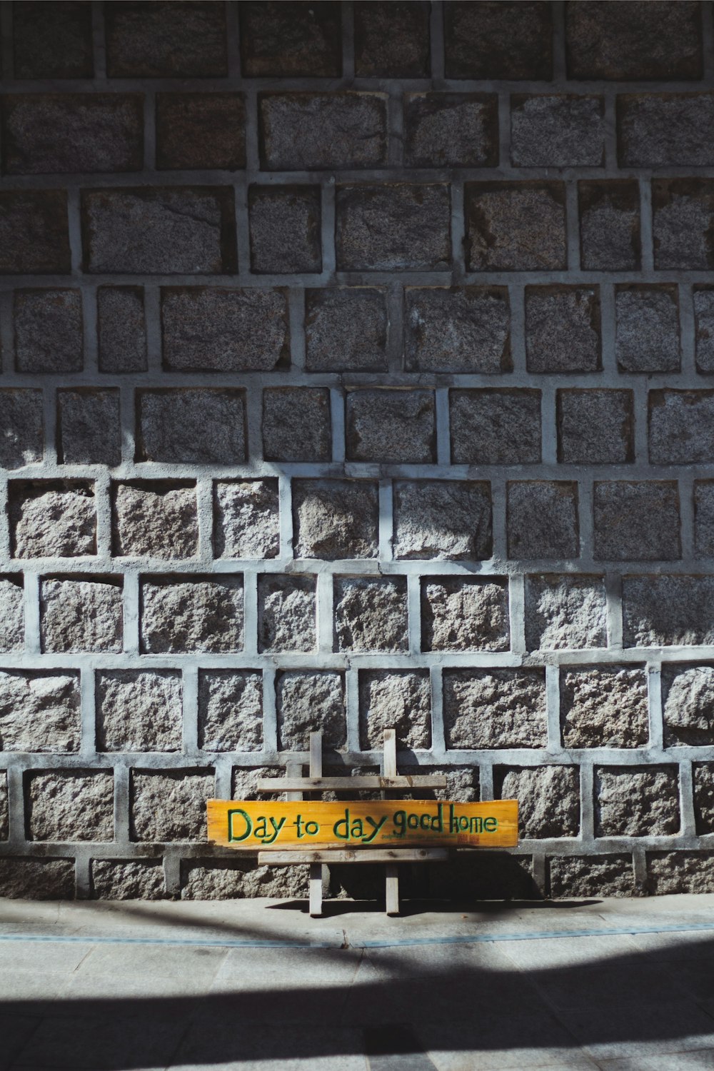 yellow and white wooden signboard with brown brick wall