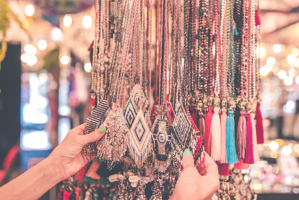 person holding beaded necklaces