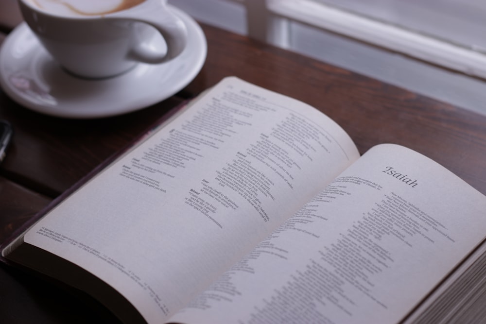 open Bible in showing Isaiah chapter on table near cup of coffee