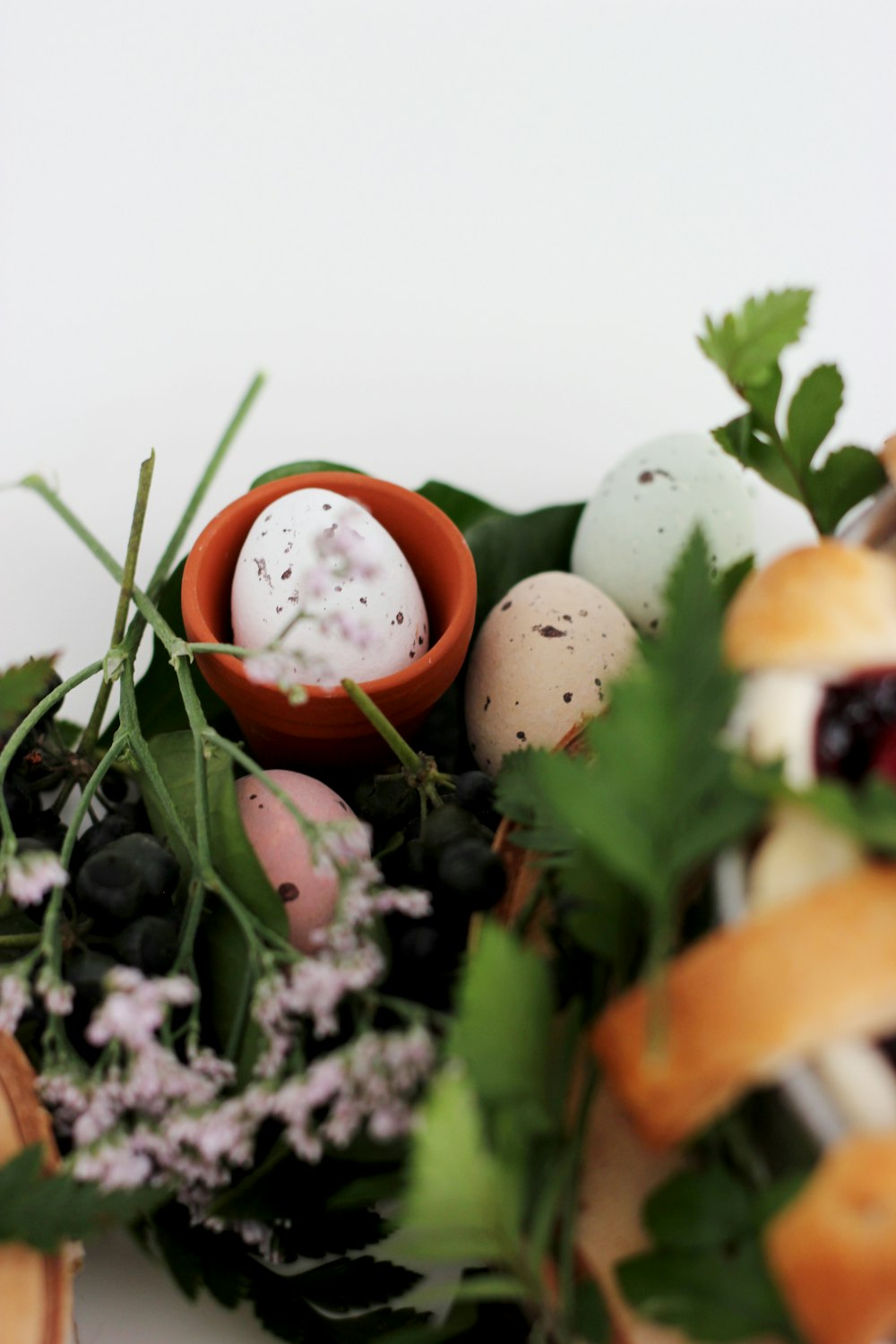 Huevos orgánicos de colores variados junto a una flor de pétalos rosados