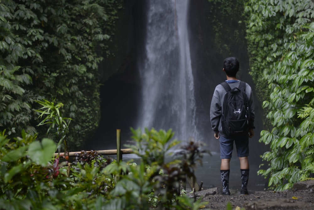 Un homme avec un sac à dos debout devant une cascade