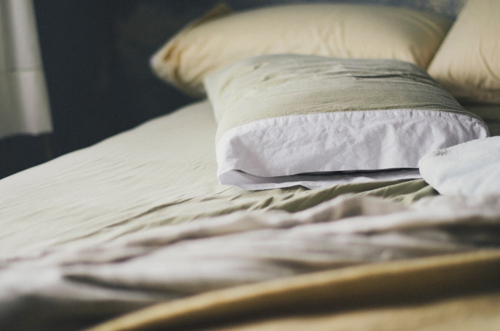 a bed with a white comforter and pillows