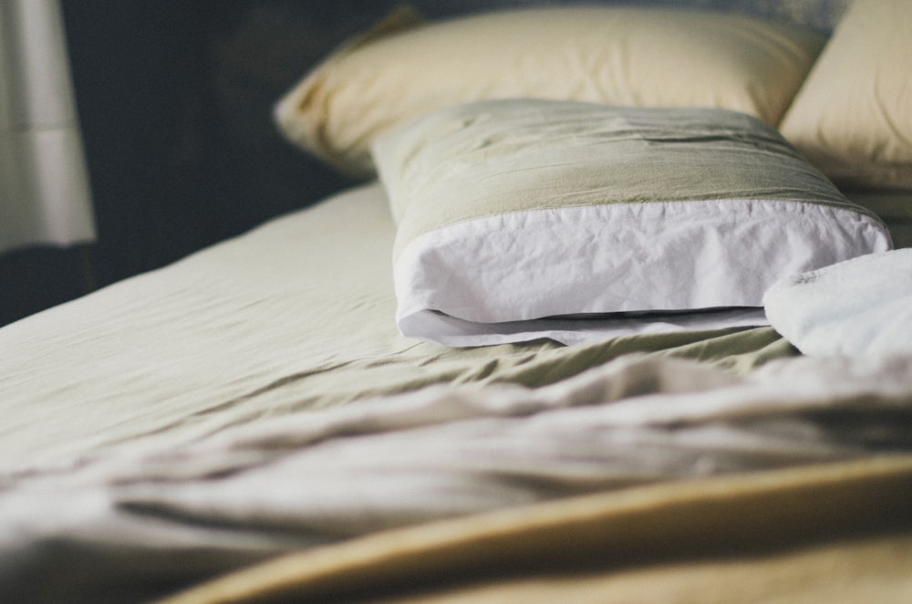 una cama con edredón blanco y almohadas