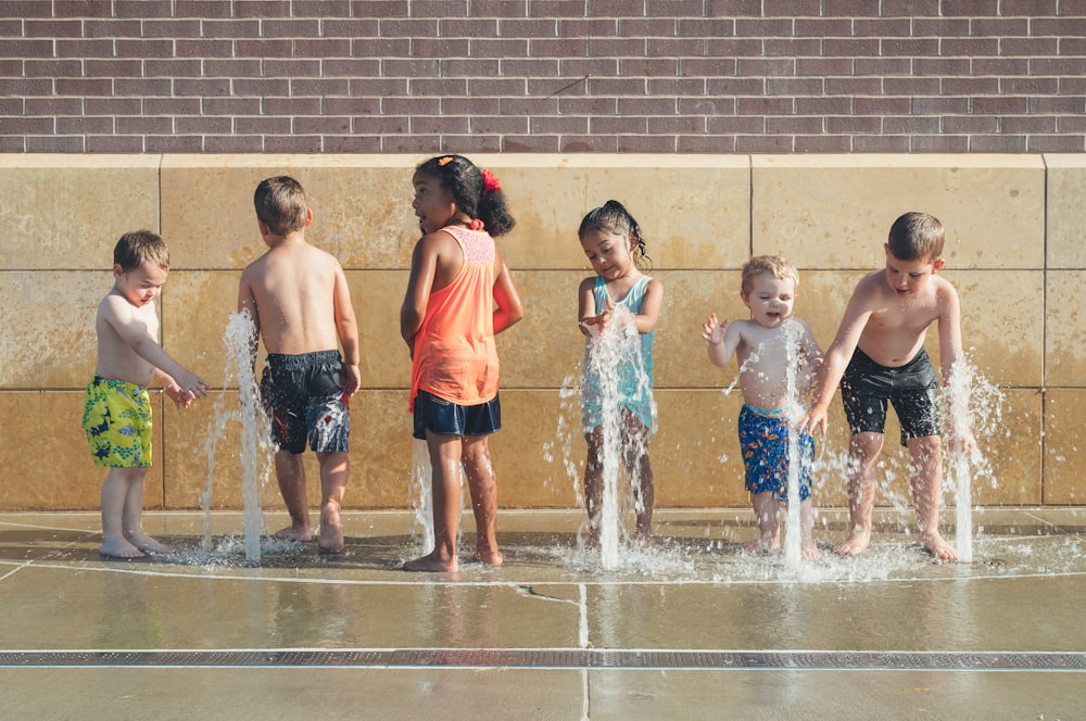 Cinco niños jugando al agua durante el día