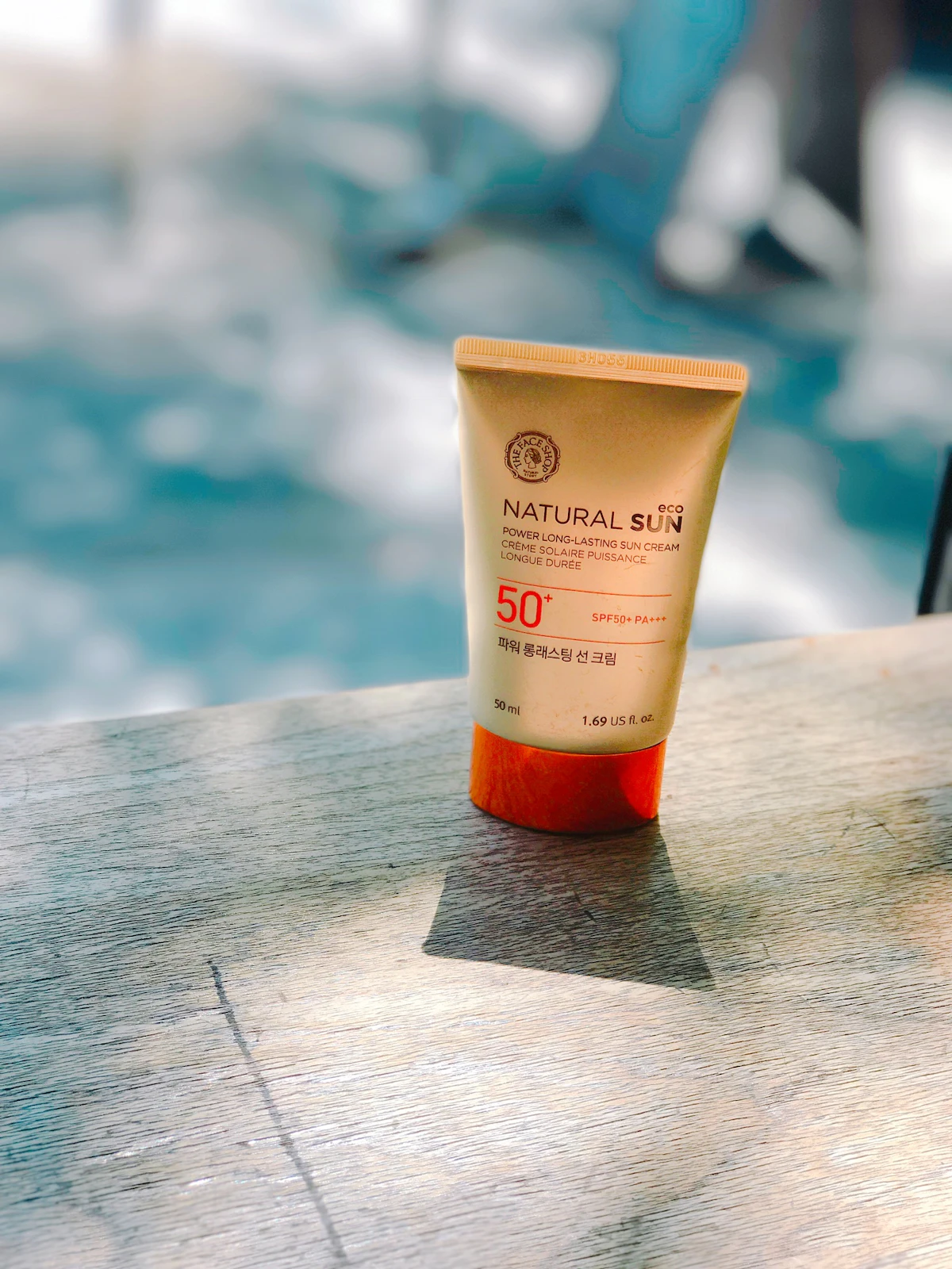 A natural mineral sun cream bottle sitting on a bathroom counter beside a small towel