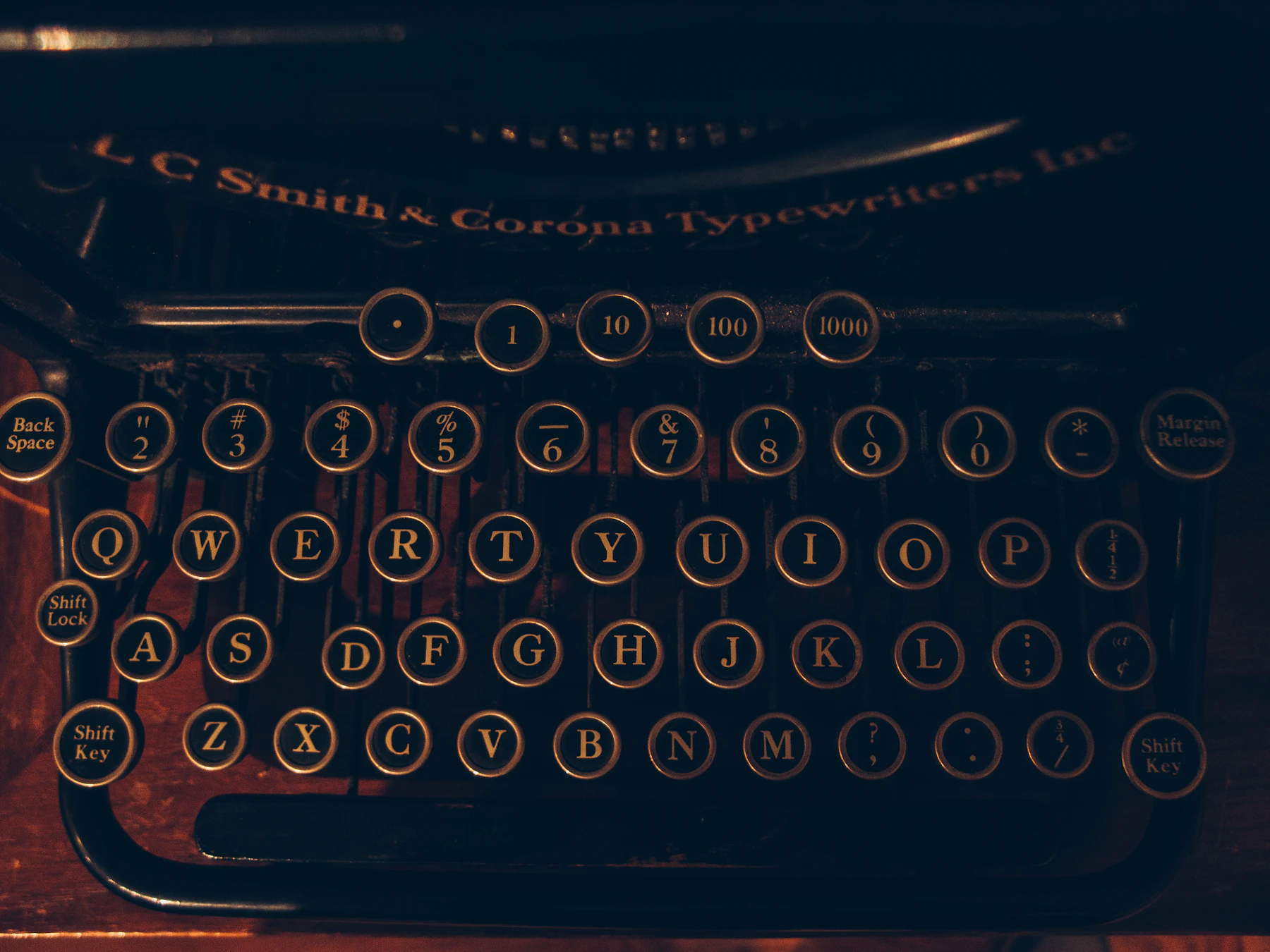 The glass-topped keys of a black prewar typewriter in warm light