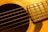 Close-up of a well-worn vintage acoustic guitar resting on a wooden floor.