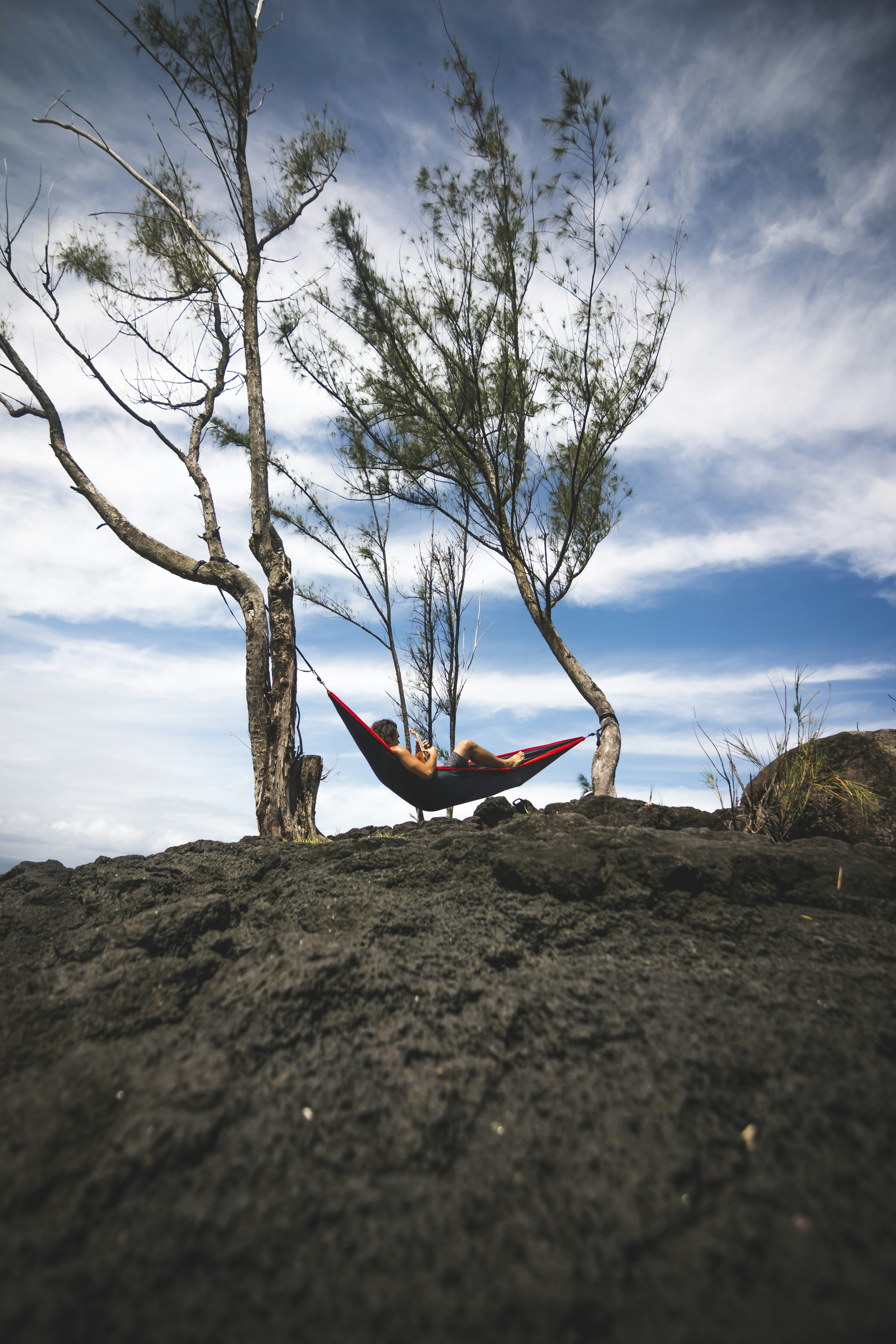 person lying on black and red hammock during daytime