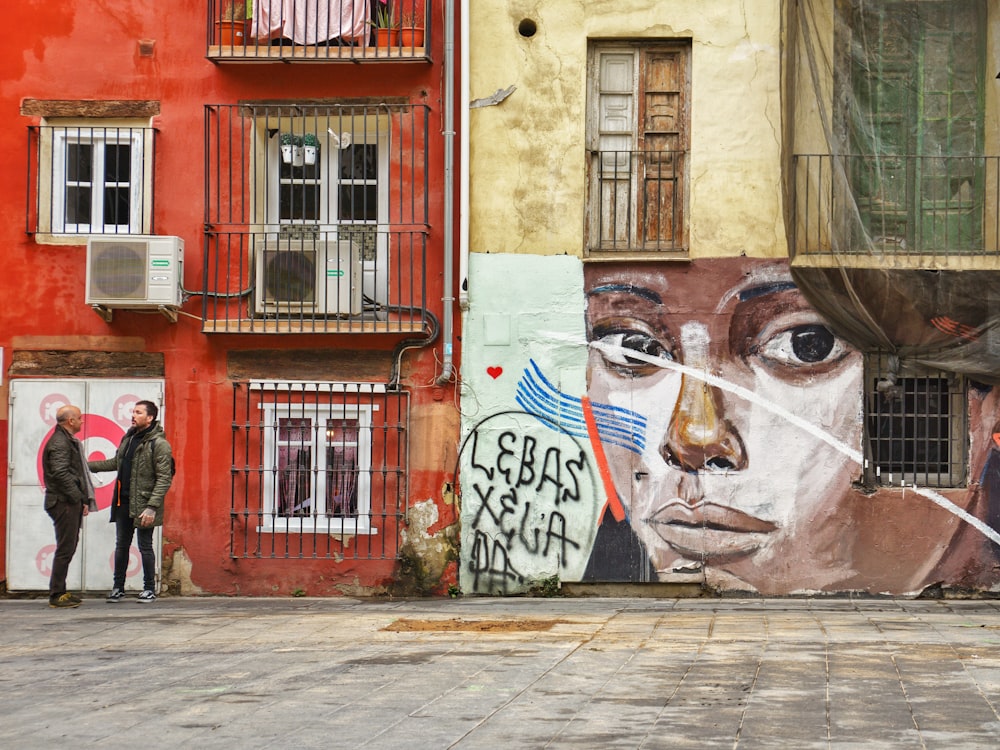 two persons talking beside graffiti