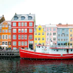 assorted-color buildings near red boat docked on port during daytime