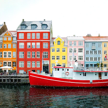 assorted-color buildings near red boat docked on port during daytime