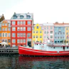 assorted-color buildings near red boat docked on port during daytime