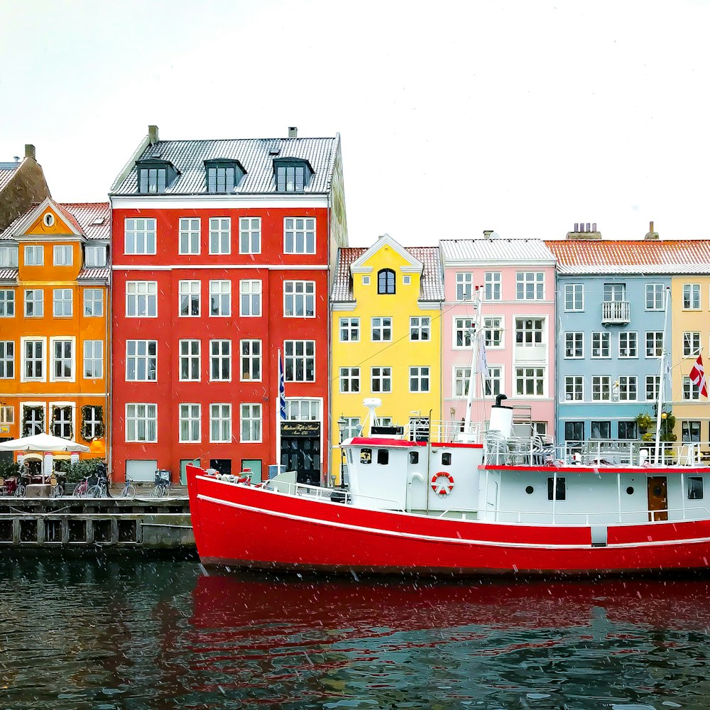 Verschiedenfarbige Gebäude in der Nähe eines roten Bootes, das tagsüber im Hafen angedockt ist