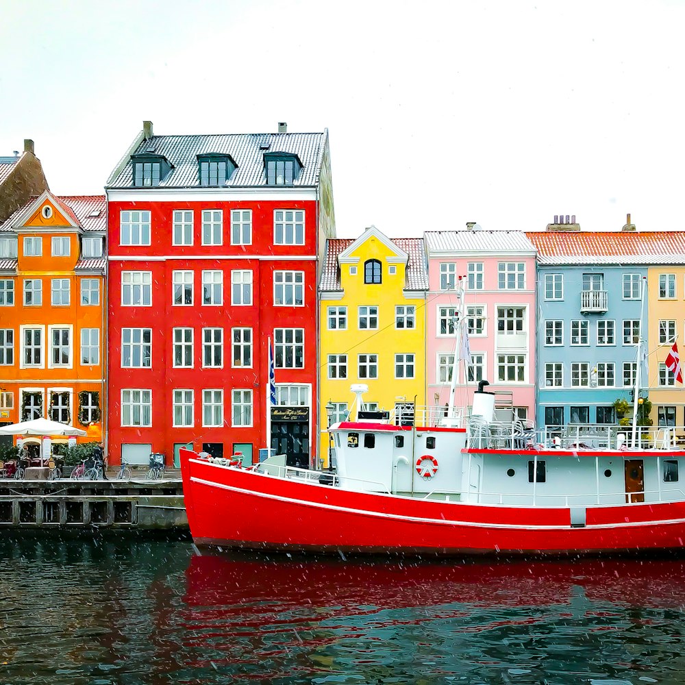 assorted-color buildings near red boat docked on port during daytime