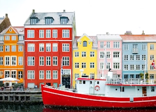 assorted-color buildings near red boat docked on port during daytime