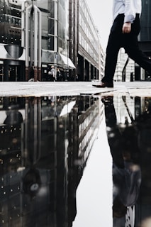 man walking near puddle of water casting reflection