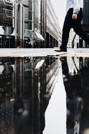 man walking near puddle of water casting reflection