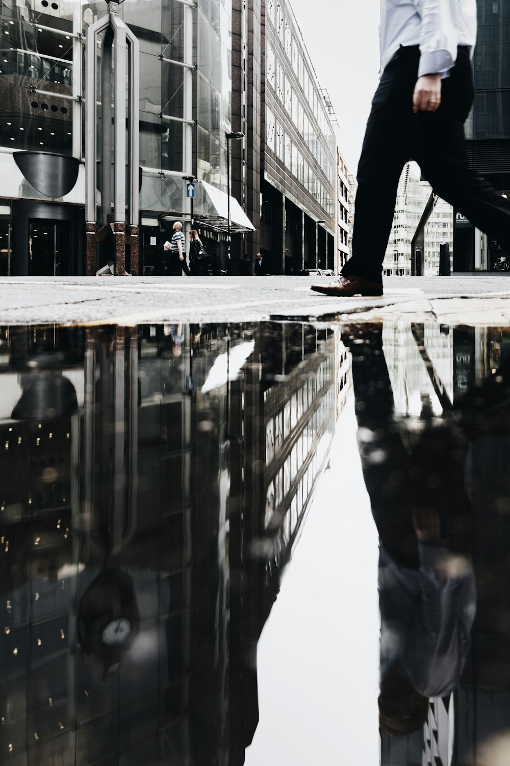 man walking near puddle of water casting reflection