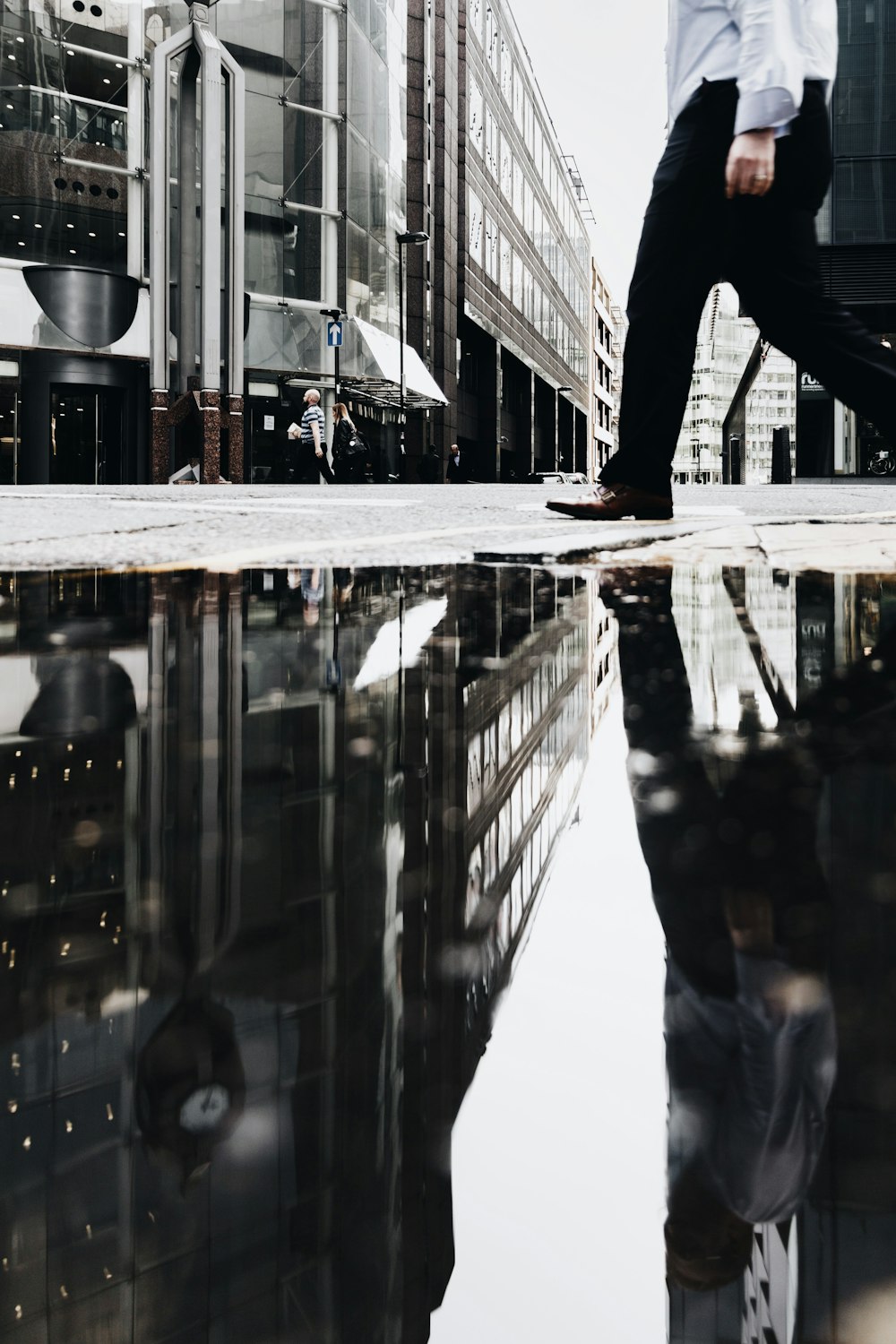 Mann, der in der Nähe einer Wasserpfütze spazieren geht, die Reflexion wirft