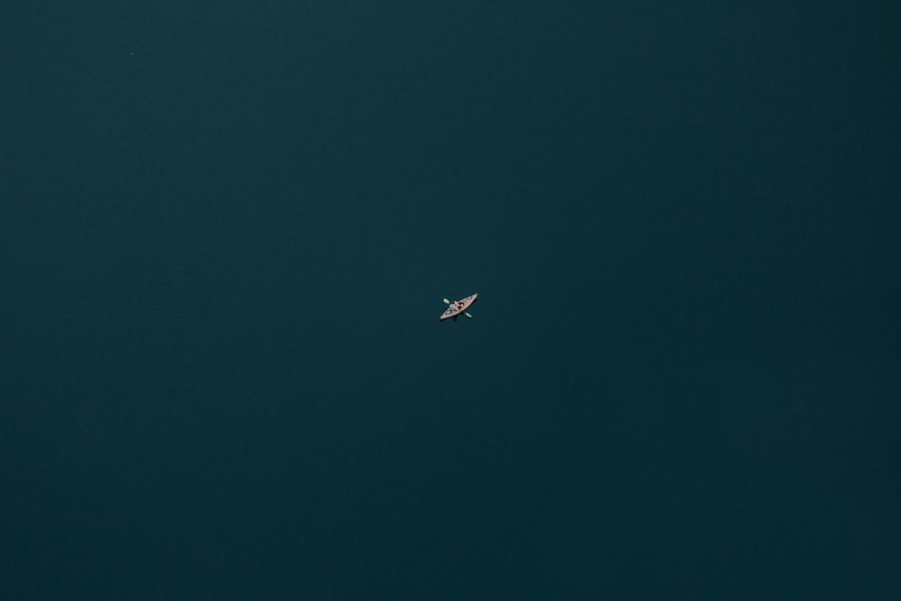 bird's-eye view photography of person riding boat with paddle in body of water