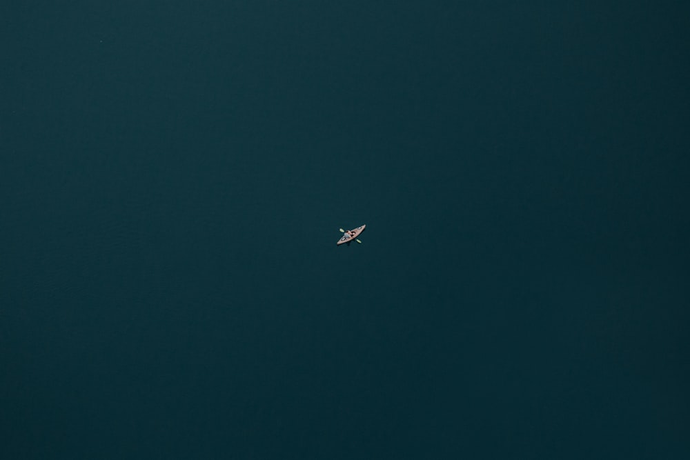 Fotografie aus der Vogelperspektive einer Person, die mit einem Paddel im Gewässer Boot fährt