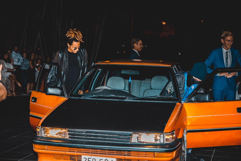 group of men riding on orange and black sedan