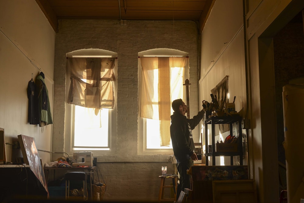 man wearing black hoodie near window