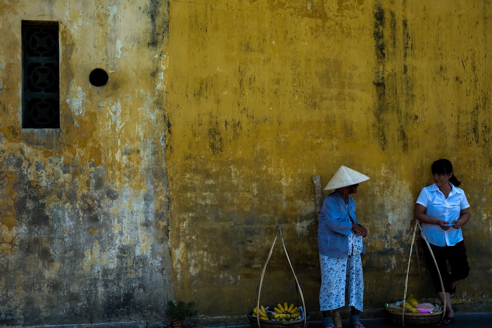 photo of two woman standing leaning on wall