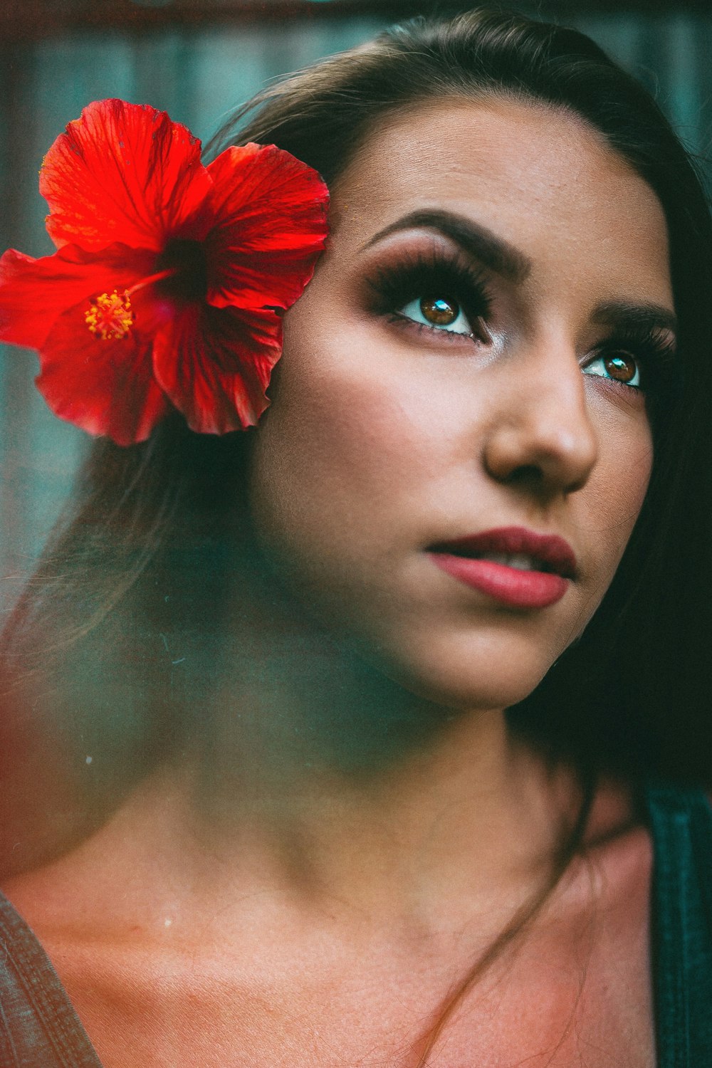 mujer con flor de hibisco rojo en la oreja