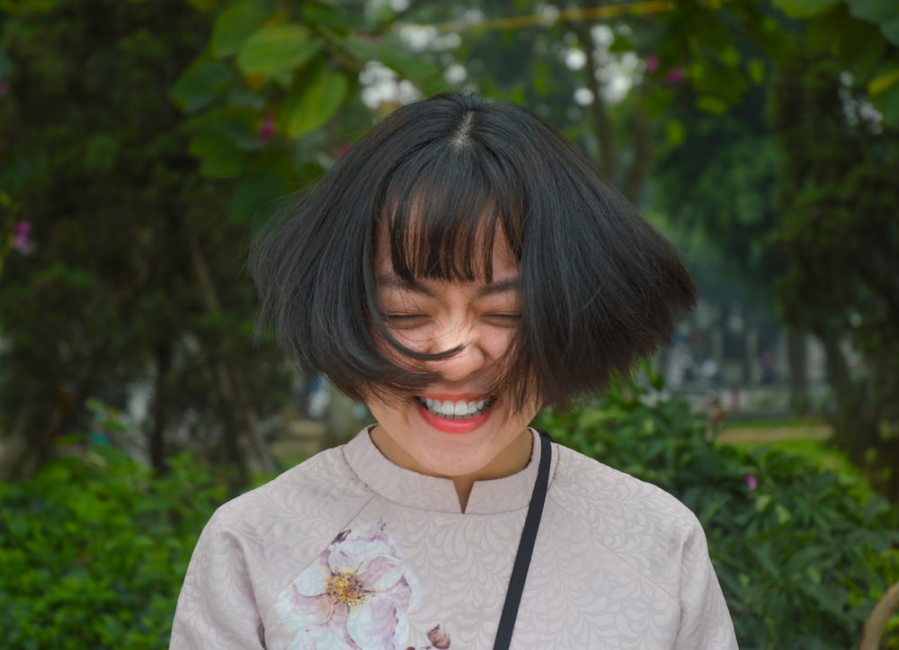 mujer sonriendo cerrando los ojos mientras se revuelve el pelo