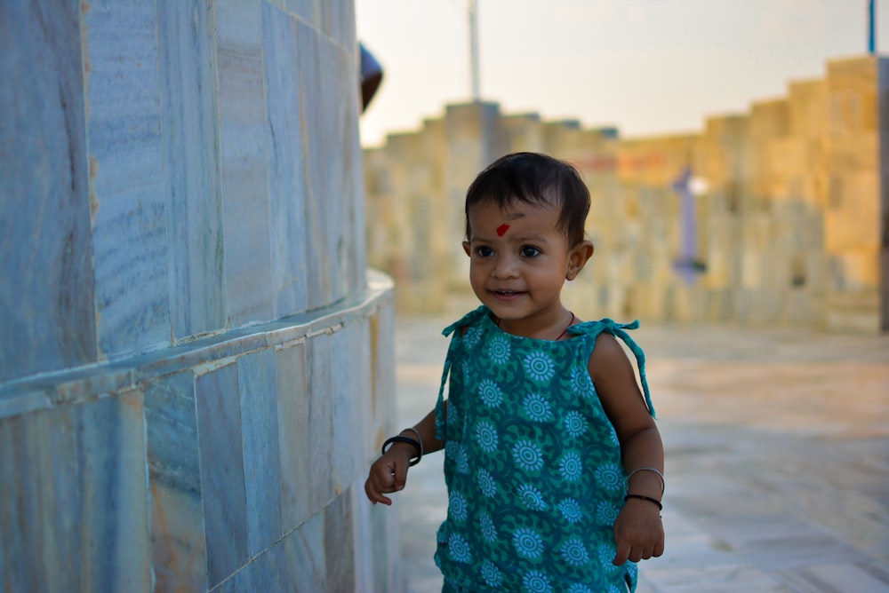 girl standing beside gray tile wall