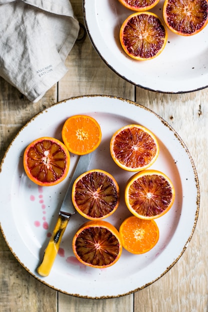 Close-up of vibrant dehydrated blood orange slices arranged artistically on a rustic wooden surface.