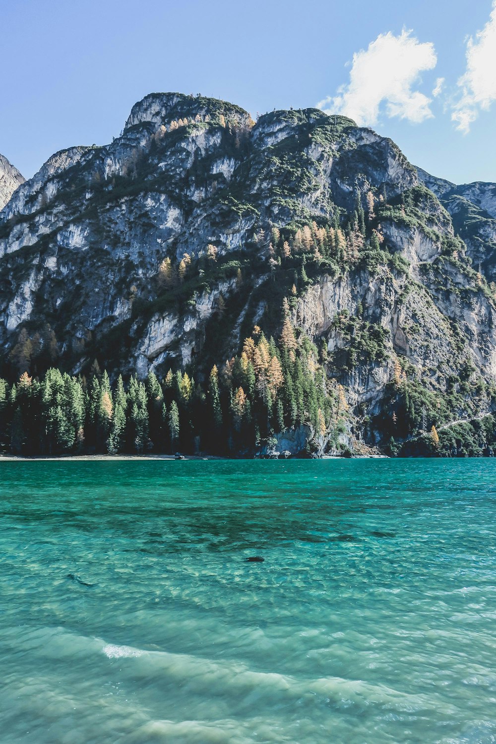 mountain surrounded by body of water under white clouds at daytime