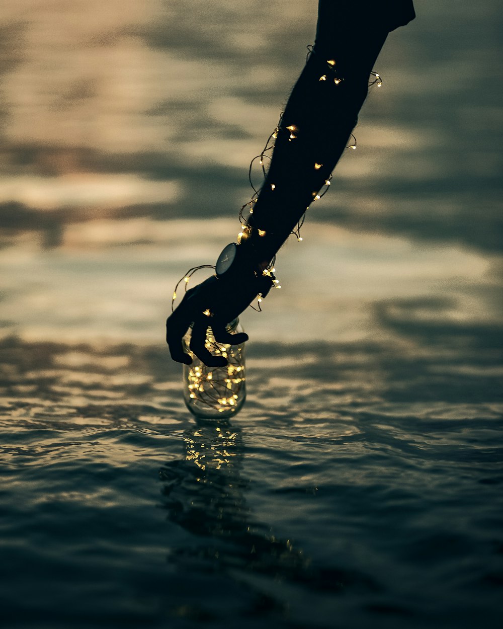 person holding mason jar with string lights