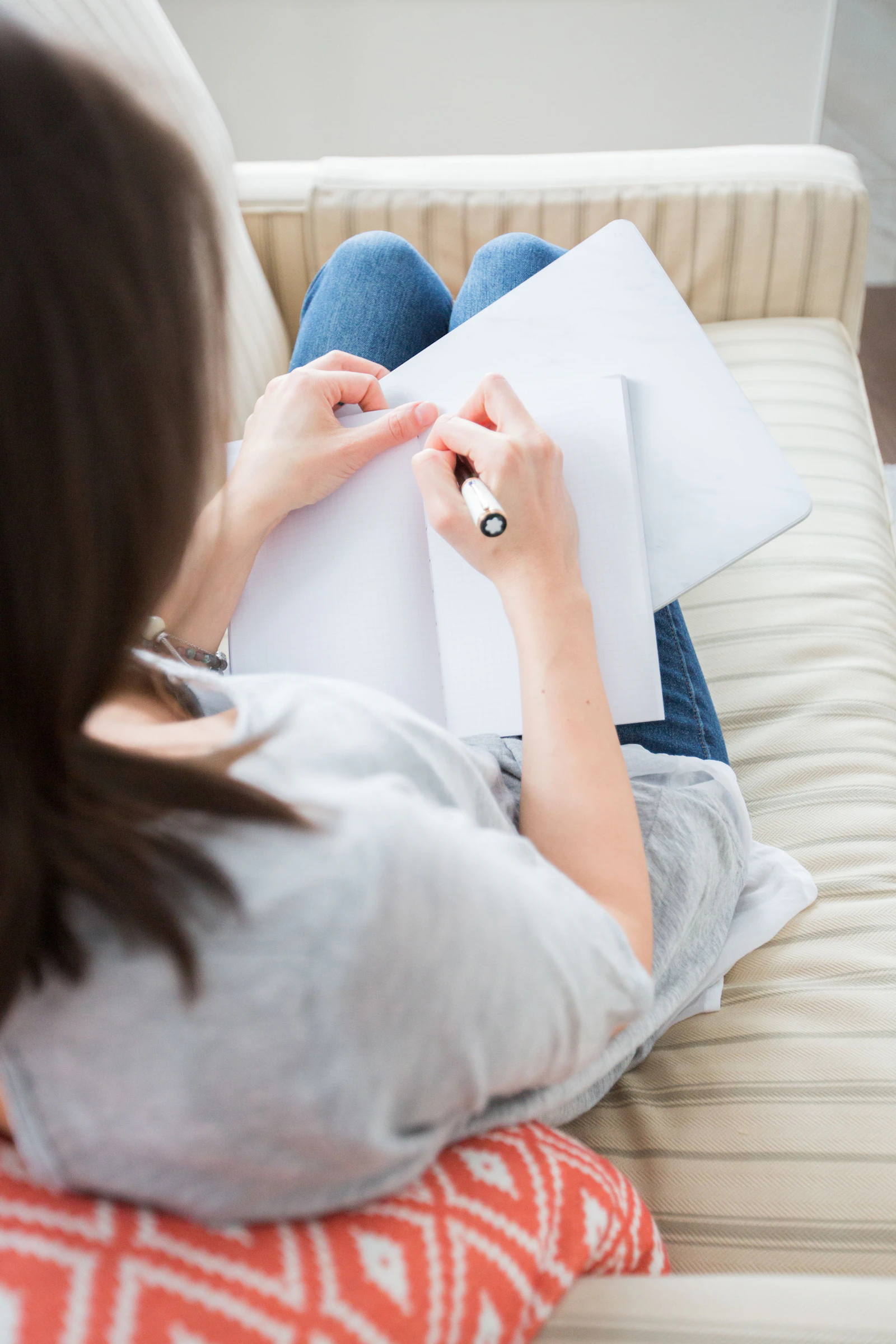 A woman writing by hand on white paper, close-up on her hand and pen.