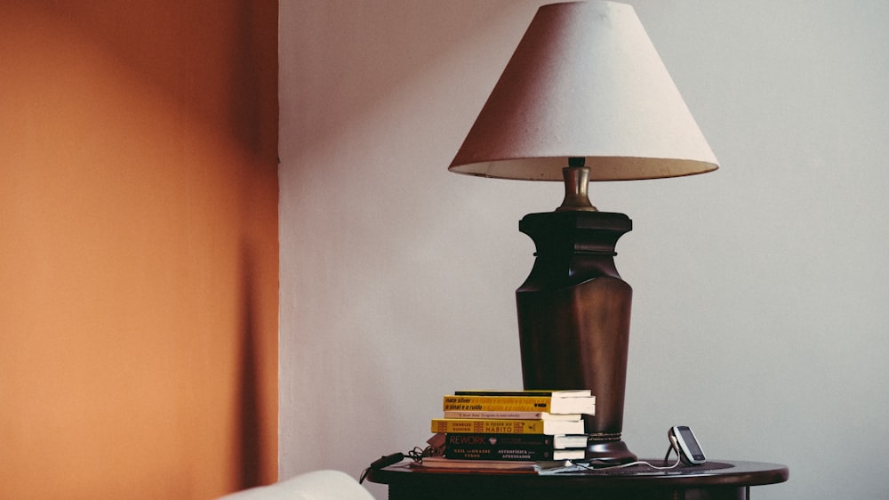 pile of books beside brown table lamp