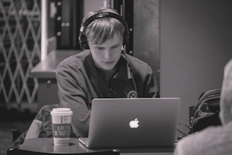 A focused student wearing headphones, engaging in an online language class from a cozy home workspace.