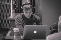 A student focused on an online lesson, headphones on, surrounded by notes and a cup of coffee.