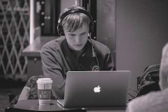 A person wearing headphones while working on a laptop.