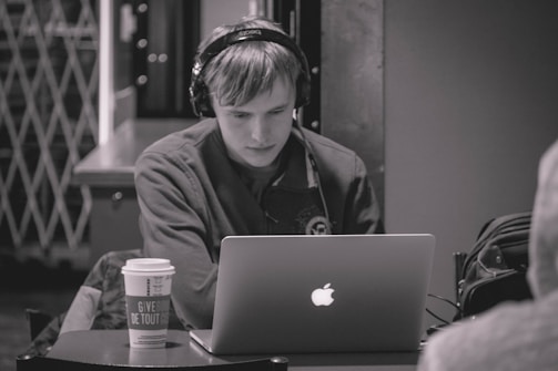 A person wearing headphones while working on a laptop.