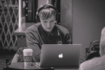A student focused on an online lesson, headphones on, surrounded by notes and a cup of coffee.
