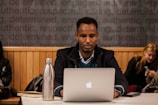 person using silver MacBook on table