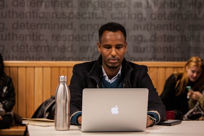 person using silver MacBook on table