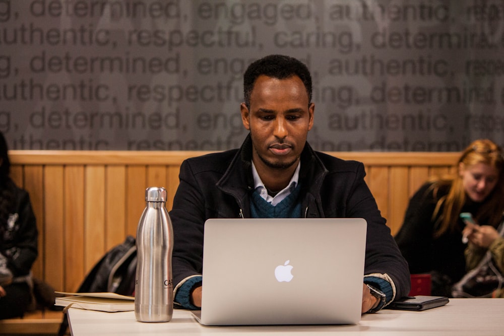 person using silver MacBook on table