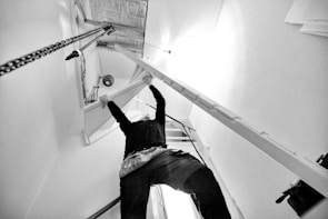 Close-up of hands tightening ductwork in a residential attic space.