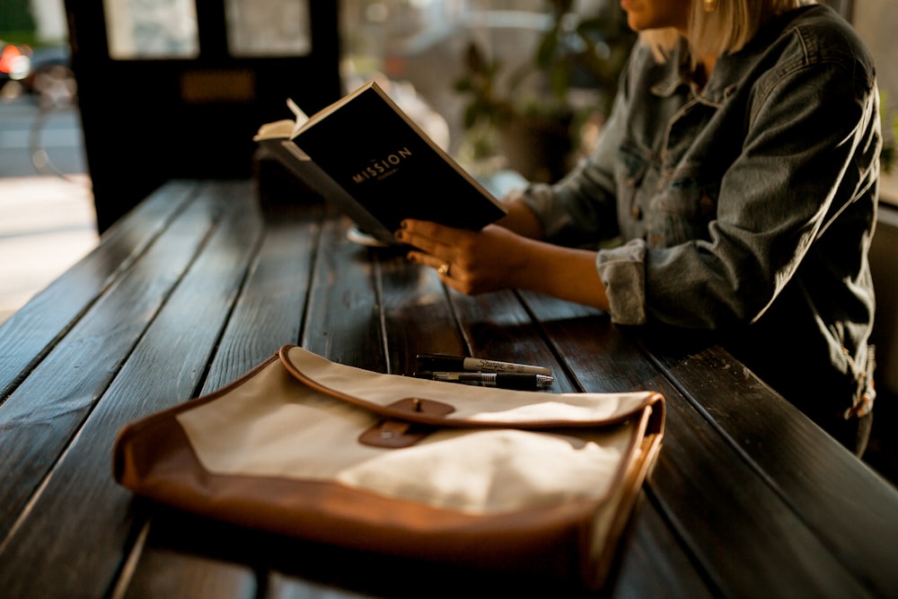 person reading a book on table