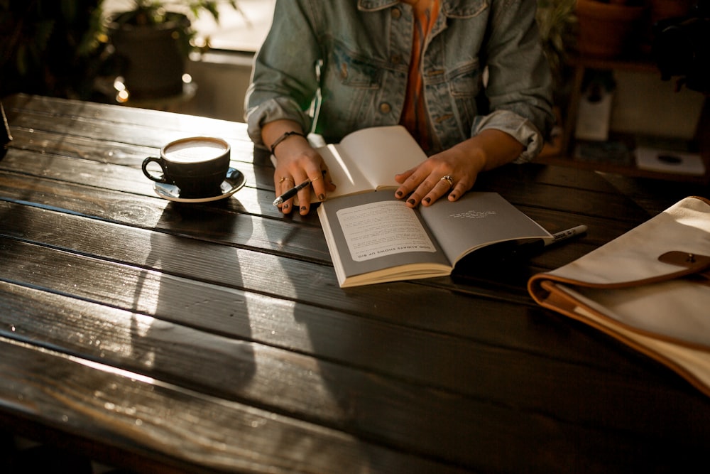 person opening notebook on brown wooden table