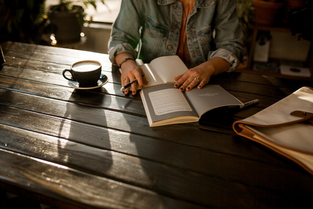 Persona abriendo cuaderno sobre mesa de madera marrón