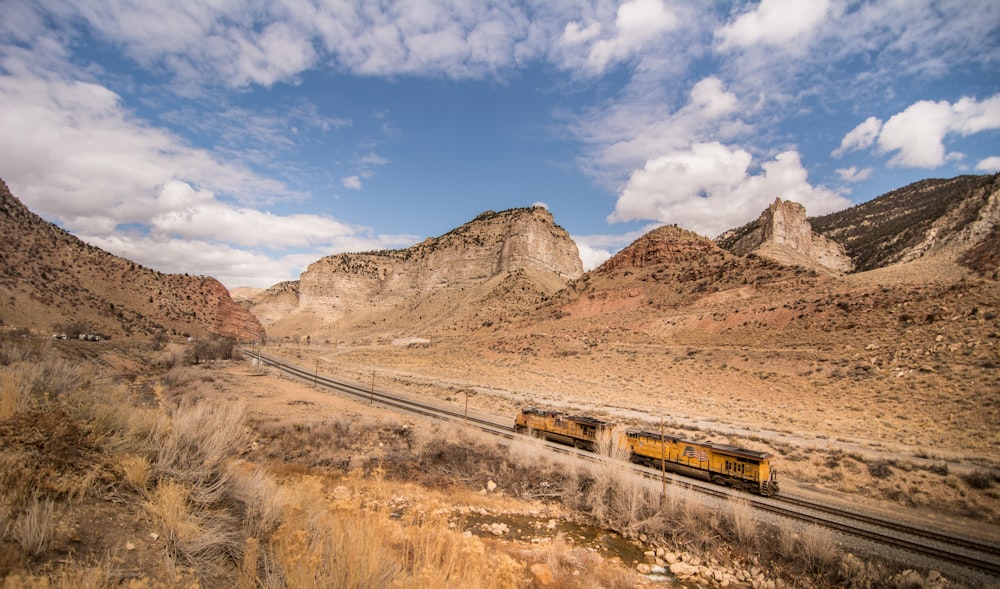 steel locomotive in railway traveling in between mountains